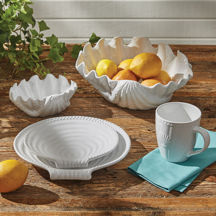 white ceramic seashell dinnerware set styled on a rustic wood table with lemons and coastal accents.